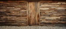 A Brown Hardwood Wall With A Rectangular Wooden Door In The Middle. The Building Material Is Wood Plank With Tints And Shades, Creating A Pattern With Wood Stain On The Flooring