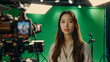 © l1gend - A beautiful young asian woman, anchor or tv presenter is getting filmed inside a green screen chroma key studio to create a video with removable background that can be replaced