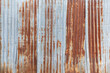 Front view of a rusty and weathered corrugated iron metal construction site wall. High resolution full frame textured grunge rust background.