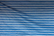 Front view of wrinkled tarp with blue and white stripes. Abstract high resolution full frame textured background.