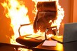 office chair on fire, with laptop and papers also burning