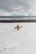© Cavan Images - Woman walking on beach with surf board winter iceland