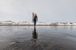 © Cavan Images - Woman walking on beach with surf board winter iceland