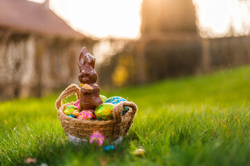 Easter eggs in basket in grass. Colorful decorated easter eggs in wicker basket. Traditional egg hunt for spring holidays. Morning magical light