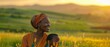 An African woman smiling and a boy standing in a green field with the boy being a bit blurry