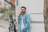 Fototapeta Panele - attractive traveler man with caravan and mobile phone