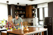 © BGStock72 - Pair enjoying a lighthearted conversation with fresh juice and a healthy breakfast spread on the counter