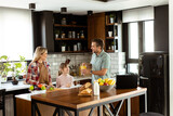 Fototapeta Tematy - Family chatting and preparing food around a bustling kitchen counter filled with fresh ingredients and cooking utensils