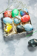Happy Easter. Natural dyed colorful eggs in paper tray on concrete board in rustic style.