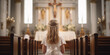 Girl with pale skin in a white gown standing at the church altar with candles and a crucifix. Back shot attending a religious service or ceremony. First communion concept.