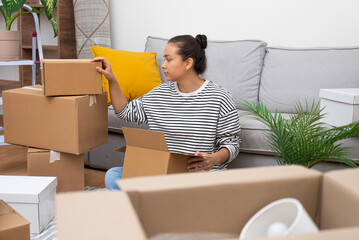 Aufkleber - Woman decomposes boxes close to cozy couch in modern house waiting for lovely husband from work to help sort out things for stylish decoration contemporary flat