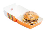 Fototapeta Dziecięca - Appetizing burger in craft paper packaging. Delicious garbage food. Isolated on a white background. Close-up.