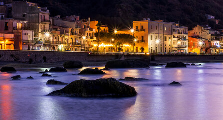 Wall Mural - evening or night landscape of sea gulf with calm water and beautiful evening town highlighted with with lanterns and flashlights