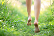 legs and feet of barefoot woman running through grass
