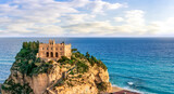 Fototapeta Krajobraz - sea landscape of beautiful white temple or castle on a high cliff isle on a rock in crystal clear turquoise sea with waves and beautiful sunset or sunrise on background of seascape