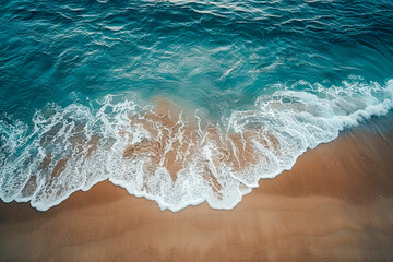  Soft wave of blue ocean gently lapping onto a sandy beach with clear water and subtle foam on the shoreline.