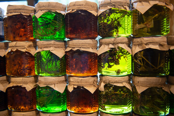 Assorted herbal tinctures in glass jars with craft paper lids.