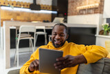 Fototapeta Młodzieżowe - African american man in yellow hoodie with tablet in hands