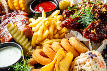 Poster - A tantalizing platter of fast food: glazed ribs, crispy fries, onion rings, and dipping sauces. Fresh herbs add a finishing touch