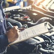 Professional mechanic inspecting car engine and writing checklist in an auto repair shop, showcasing thorough maintenance and repair estimation.