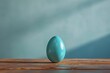 a blue egg on a wood surface