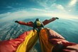 A person gracefully floats in the sky, enveloped in a vibrant orange and yellow parachute.
