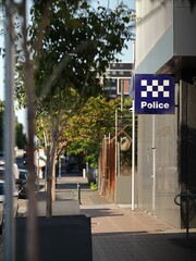 Sunny street scene with a police station sign visible in the foreground