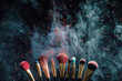 Makeup brushes with powder explosion on dark background