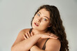 © LIGHTFIELD STUDIOS - portrait of curvy woman in her 20s with curly brown hair and blue eyes covering hands to neckline
