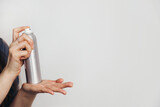 Fototapeta Konie - Female hand hold small metallic spray bottle on white background.