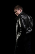 Serious man in a leather jacket looks to the side on a black background. A thoughtful and confident person. Dramatic photo.