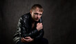 Serious man in a leather jacket looks to the side on a dark abstract background. A thoughtful and confident person. Dramatic photo.
