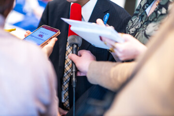 Wall Mural - News conference, journalists taking notes, holding microphone and digital voice recorder interviewing unrecognizable politician or business person during media event