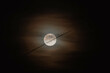 Mond hinter dünnen Wolkenschleier mit Kondensstreifen
