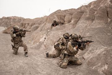 Soldiers in camouflage uniforms aiming with their rifles.ready to fire during military operation in the desert , soldiers training  in a military operation