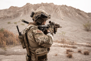 Soldiers in camouflage uniforms aiming with their rifles.ready to fire during military operation in the desert , soldiers training  in a military operation