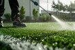 person spraying water on artificial turf for cleaning