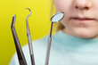 Dental instruments against the background of the mouth of a seven-year-old girl. Surgical dentistry concept, removal of baby teeth and treatment of caries, close-up