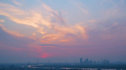 Wall Mural - Time lapse interval sunset over modern office buildings in business district. Skyline cirrus cloudscape view of cityscape with disc sun sunlight and flare.