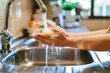 person at kitchen sink washing hands with dish soap