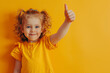 A young child giving a thumbs up, set against a bright yellow background