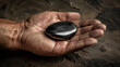 An image capturing a shiny black stone on the textured surface of a hand, suggesting themes of contrast and human touch