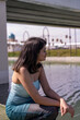 © oybekostanov - A woman is sitting on a bridge near a body of water