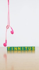 Single word TINNITUS and pink headphones