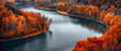 A tranquil river winding through a forest, with the colors of the autumn leaves forming a splendid gradient along the banks, captured in high-definition to highlight its mesmerizing vibrancy.