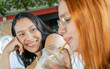 mujeres jóvenes latinas compartiendo una café en una tarde juntas y cuentan historias una de ellas le sonríe y mira con admiración 