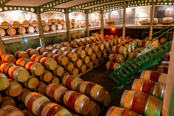 Wall Mural - French oak wooden barrels for aging red wine in underground cellar, Saint-Emilion wine making region picking, cru class Merlot or Cabernet Sauvignon red wine grapes, France, Bordeaux