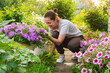 © Юлия Завалишина - Gardening and agriculture concept. Young woman farm worker gardening flowers in garden. Gardener planting flowers for bouquet. Summer gardening work. Girl gardening at home in backyard