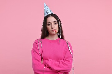 Sticker - Sad woman in party hat with blower and streamers on pink background