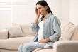 © New Africa - Pregnant woman suffering from headache on sofa at home